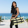 Beautiful woman in black outfit with yellow black duffle bag on coastal terrace