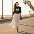 Long-haired woman in black coastal hearts sweatshirt with flowing white maxi skirt