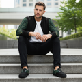 Man in bomber and matching shoes sitting, green leaf design clearly visible