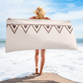 Woman holding beige geometric triangle beach towel on coastal beach